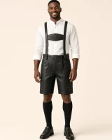 Man in his thirties wearing the Rossstein black lederhosen with a white stand-collar Trachten shirt, full-length front